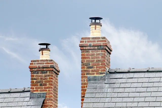 Close-up of traditional brick chimneys on a slate roof, England. 5 things worth knowing about chimney sweep pricing and profit