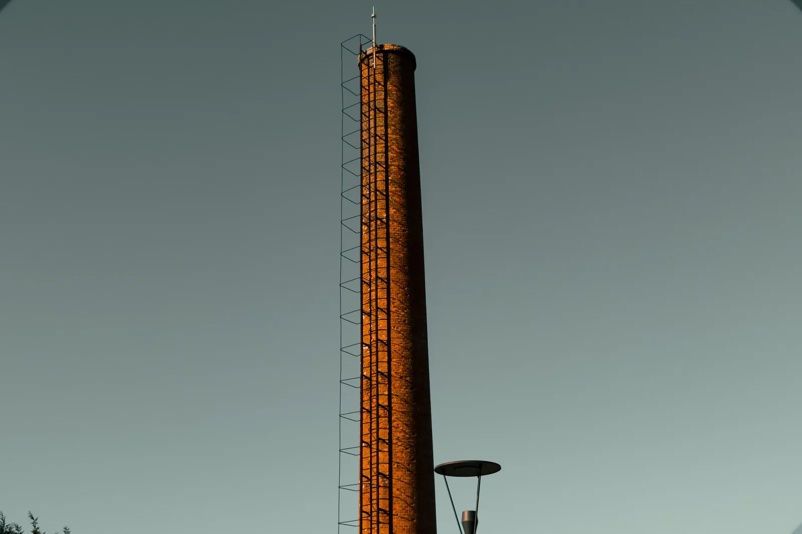 Tall industrial chimney with ladder against a clear sky backdrop, no pollution visible. On-time chimney sweep: scheduling that works