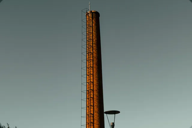 Tall industrial chimney with ladder against a clear sky backdrop, no pollution visible. On-time chimney sweep: scheduling that works