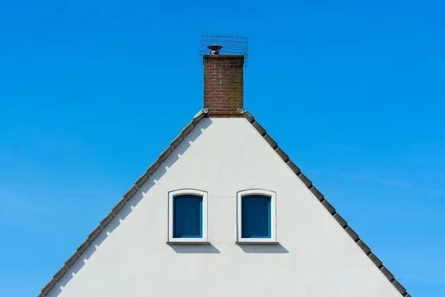 A minimalist house facade with a chimney against a bright blue sky, showcasing symmetry and simplicity. Winning more chimney sweep customers on the job: visit, quote and review
