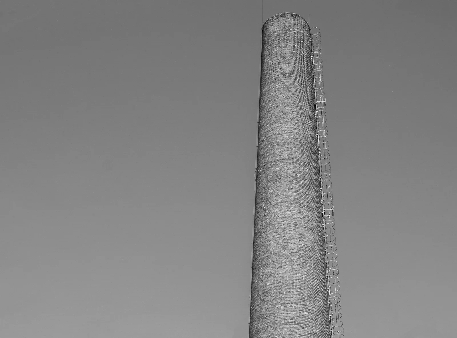 A tall industrial chimney reaching into the sky, captured in black and white. WETT certification chimney sweep Canada: how it works