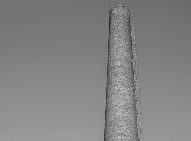 A tall industrial chimney reaching into the sky, captured in black and white. WETT certification chimney sweep Canada: how it works